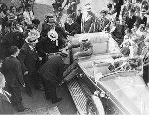 FDR being assisted by several attendants while exiting his car.